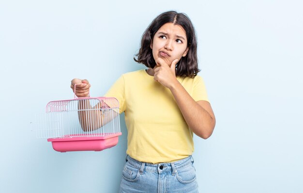 Pretty young woman thinking, feeling doubtful and confused. pet cage concept