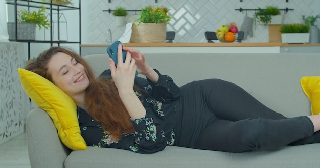 ソファでスマートフォンを使用しているかなり若い女性