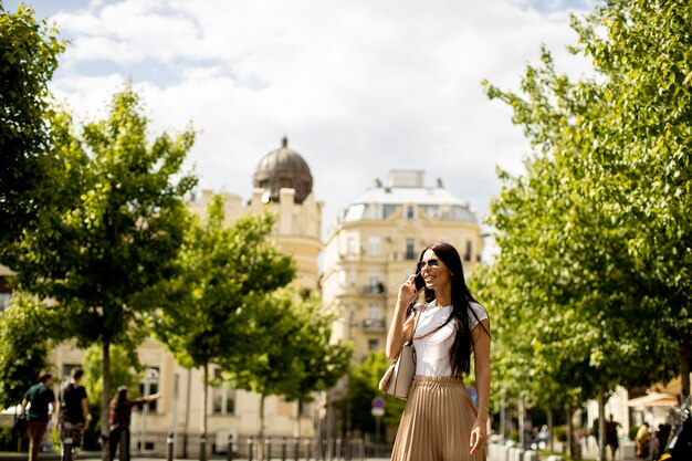 Pretty young woman using a mobile phone while walking in the street