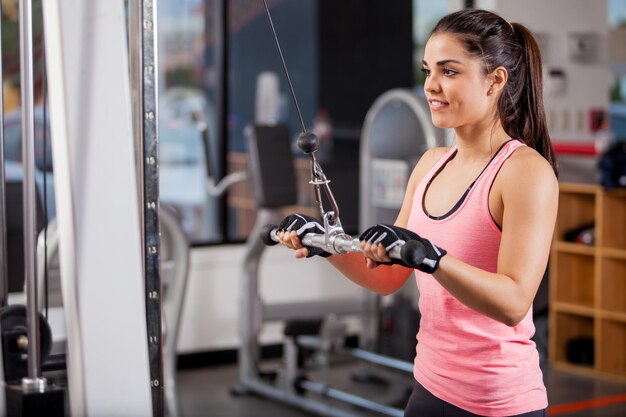 Professional woman athlete using the pulley machine Stock Photo by