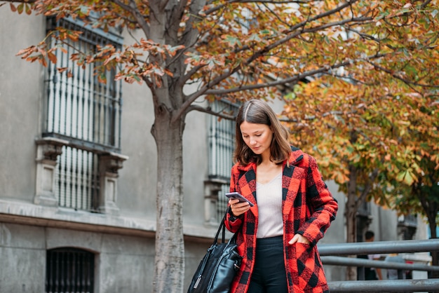 Pretty young woman walking on the street using phone