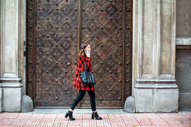 Pretty young woman walking on the street using phone