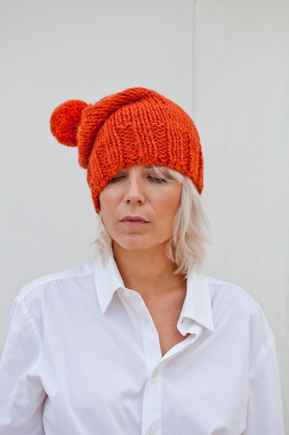 Довольно молодая женщина в теплой оранжевой шапочки.
