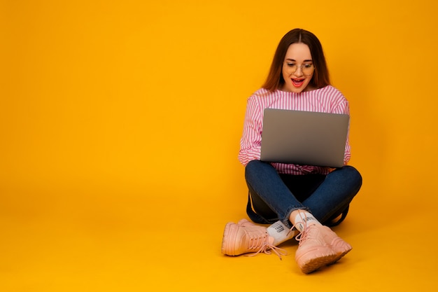 Pretty young woman wearing a stylish pink t-shirt on yellow background