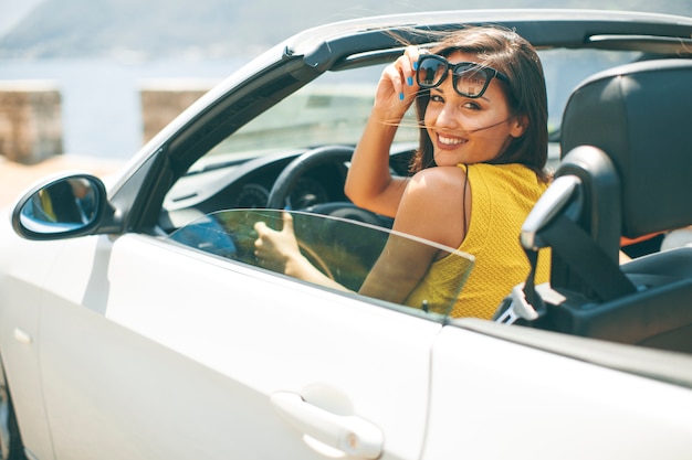 Pretty young woman in white cabriolet car