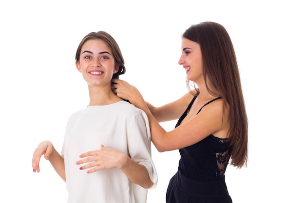 Pretty young woman in white shirt talking to another one on white background in studio