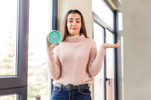 Pretty young woman wholding an alarm clock house interior design