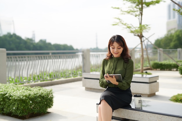 公園でタブレットを使用して美しい笑顔のかなり若い女性