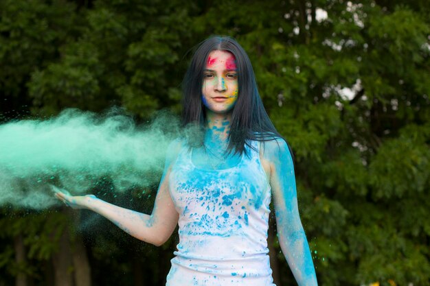 Pretty young woman with blowing color paint around her