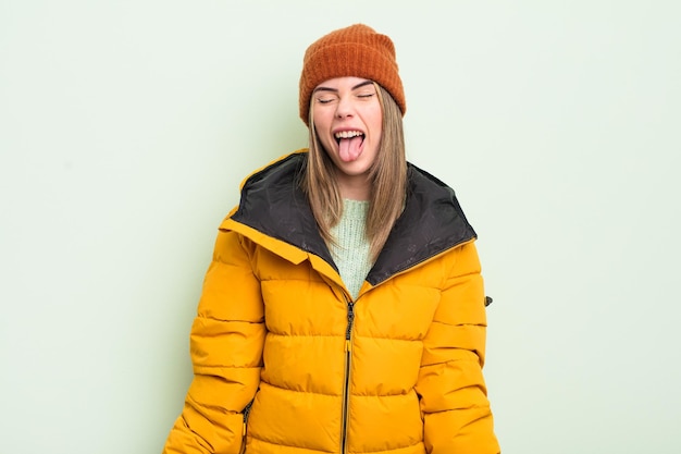 Pretty young woman with cheerful and rebellious attitude joking and sticking tongue out cold weather concept