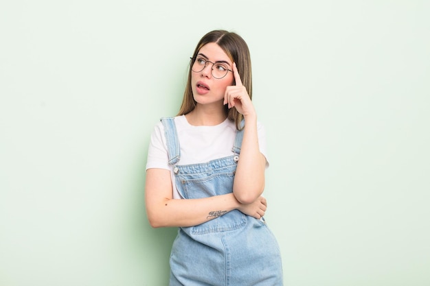 Pretty young woman with a concentrated look wondering with a doubtful expression looking up and to the side