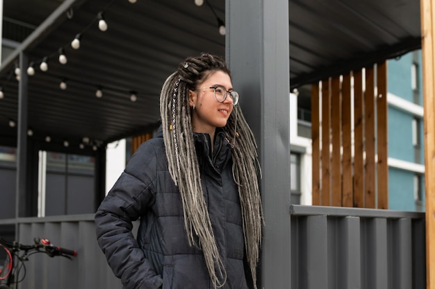 Photo a pretty young woman with a dreadlocked hairstyle dressed in a winter jacket walks around the city