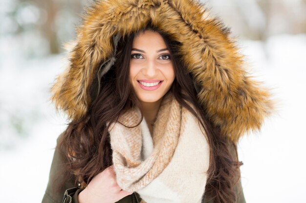 Pretty young woman with hood in the park on the winter day