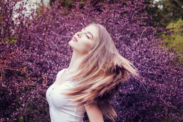 紫色の花を背景に長いストレートの髪の肖像画を持つかなり若い女性