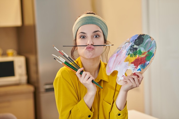 A pretty young woman with a palette and brushes in hands