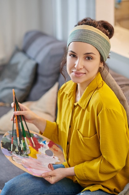 A pretty young woman with a palette and brushes in hands