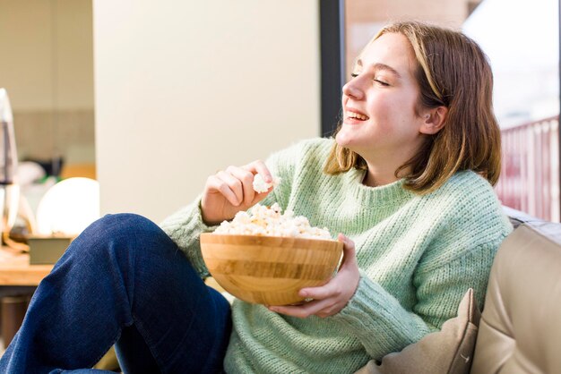 Photo pretty young woman with a popcorns bowl house interior design