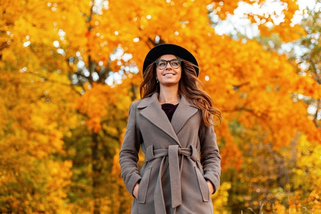 Pretty young woman with a positive smile in a stylish coat in a fashionable hat