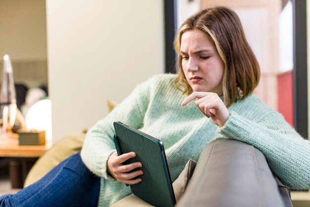 タブレット タッチ スクリーンの家のインテリア デザインを持つかなり若い女性