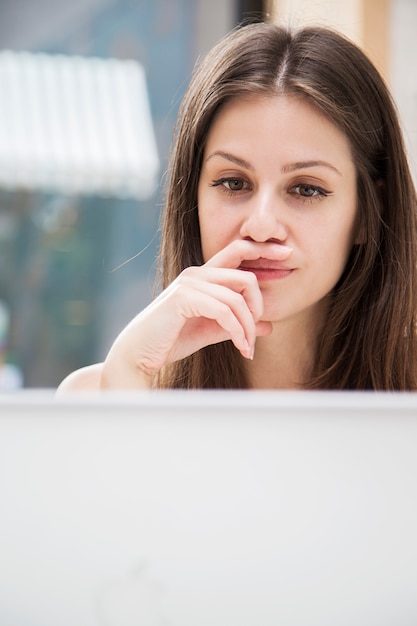 Giovane donna graziosa che lavora al computer portatile nell'ufficio