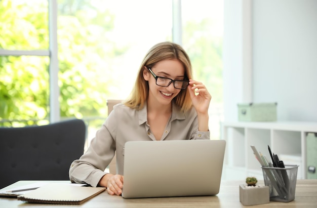 Pretty young woman working with laptop in office