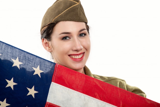 La giovane donna graziosa in wwii ci uniforma con la bandiera americana