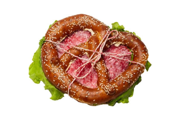 Pretzel with salami and lettuce isolated on a white surface. Tasty snack.