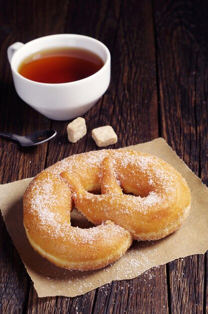 Pretzel with sugar and cup of hot tea on dark wooden table