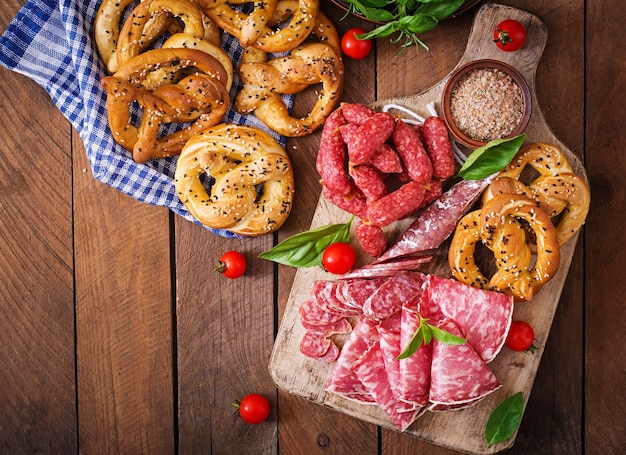 Pretzelle e varie salsicce su fondo in legno. oktoberfest.