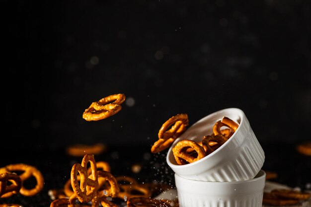 Photo pretzels with salt fall from a white cup