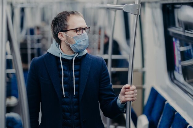 Prevention in public transport health awareness for pandemic protection Young man wears medical mask while travels by urban train protects himself from virus Covid19 outbreak in Europe