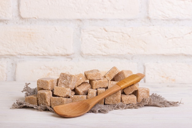 Pricked cane sugar in cubes on a linen cloth and a wooden spoon