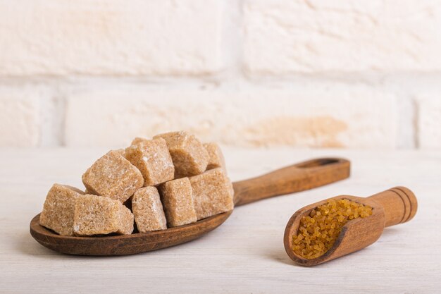 Pricked cane sugar in a wooden spoon and near sugar sand