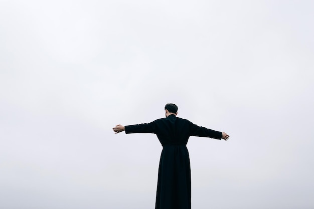 Priest bearded man raised his hands up on the hill above the town Pastor posing outdoors in mountains