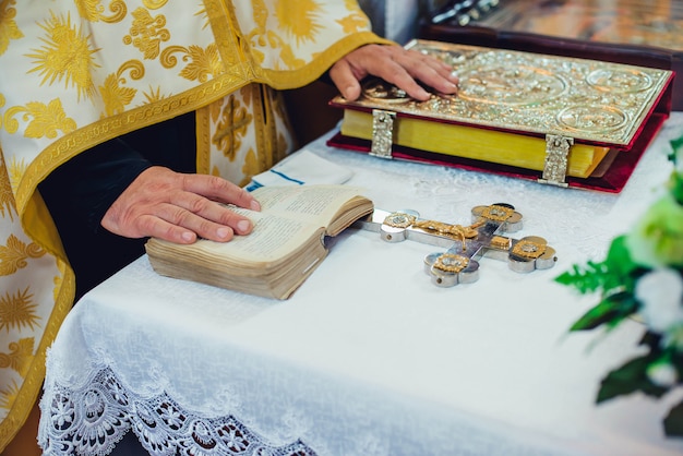 Il sacerdote tiene le sue mani sugli attributi cerimoniali nuziali sull'altare in una chiesa