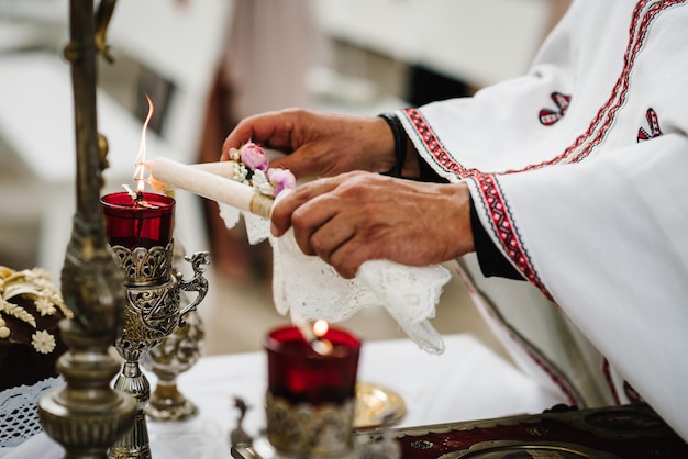 The priest lights candles before the wedding ceremony Close up