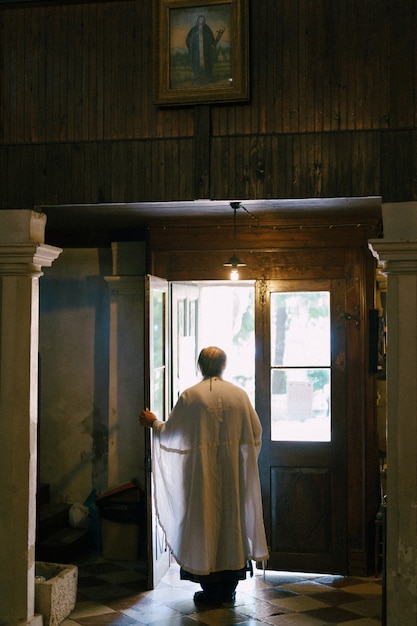 Il sacerdote apre le porte della chiesa vista posteriore