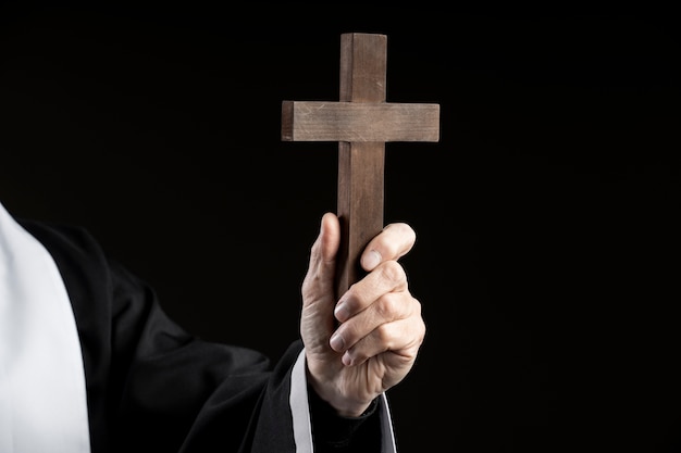 Priest's hand holding wooden cross