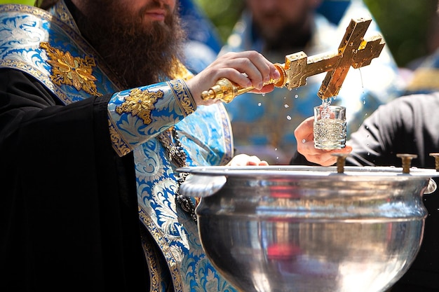 Foto il sacerdote santifica l'acqua abbassando la croce nell'acqua