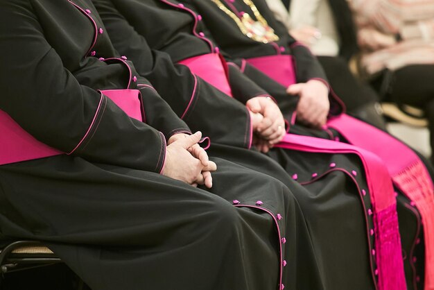 Foto i sacerdoti o i vescovi si siedono su una sedia e si tengono per mano.