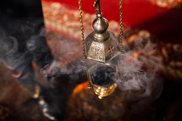 Photo a priests censer hangs on an old wall in the orthodox church copper incense with burning coal inside service in the concept of the orthodox church adoration