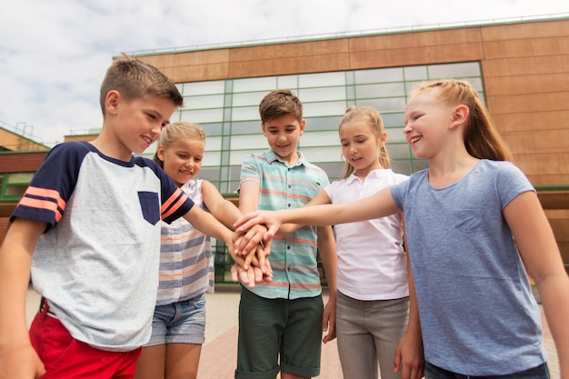Фото Начальное образование, дружба, детство и концепция людей - группа счастливых учеников начальной школы с поднятыми руками на открытом воздухе