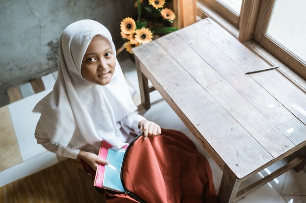 Primary indonesian school student preparing her book at home before going to school in the morning