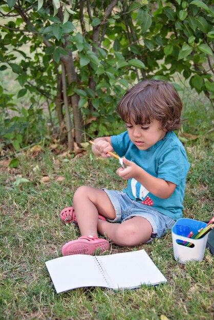 Primary school child lying on the grass doing homework