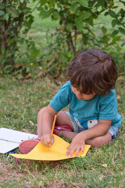 Primary school child lying on the grass doing homework