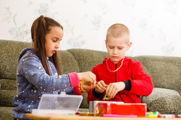 小学生の男の子と女の子は、自宅のテーブルで創造的な手作りのアートに従事しています