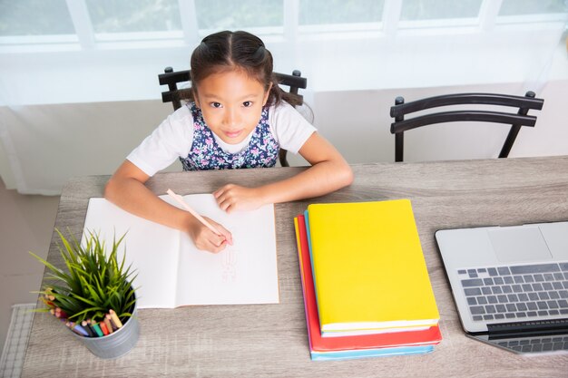 Primary school girl reading and writing book , top view