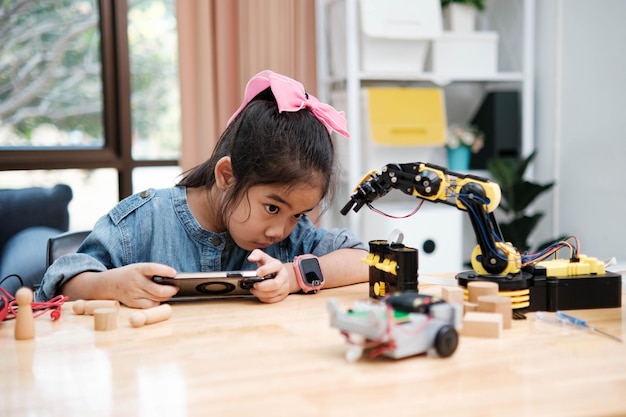 Photo primary school girl using app to control car in stem class