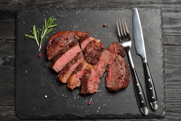 Foto prime black angus ribeye steak op zwarte stenen plaat. gemiddelde gaarheid van de biefstuk.