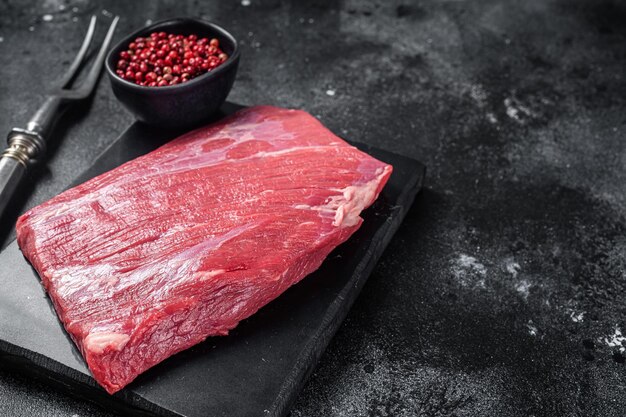 Prime choice flank steak raw beef meat on marble board with herbs Black background Top view Copy space